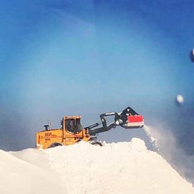 Gul gravemaskin måker snø