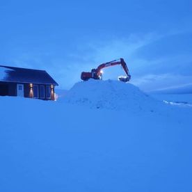 Gravemaskin måker snø