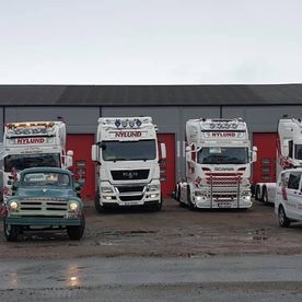 Hvite lastebiler utenfor byggning